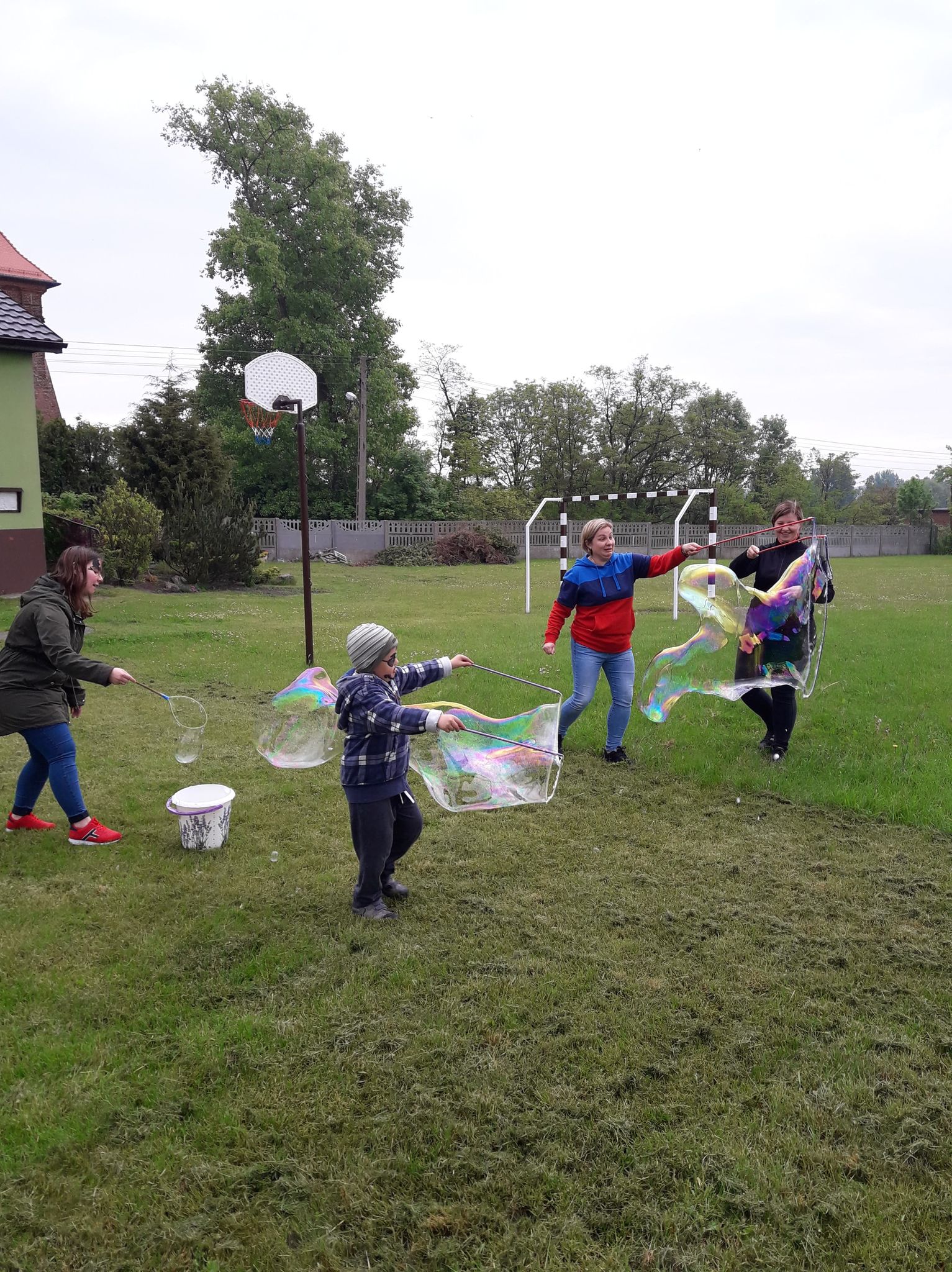 wychowawcy wraz z dziećmi robią giga bańki na boisku