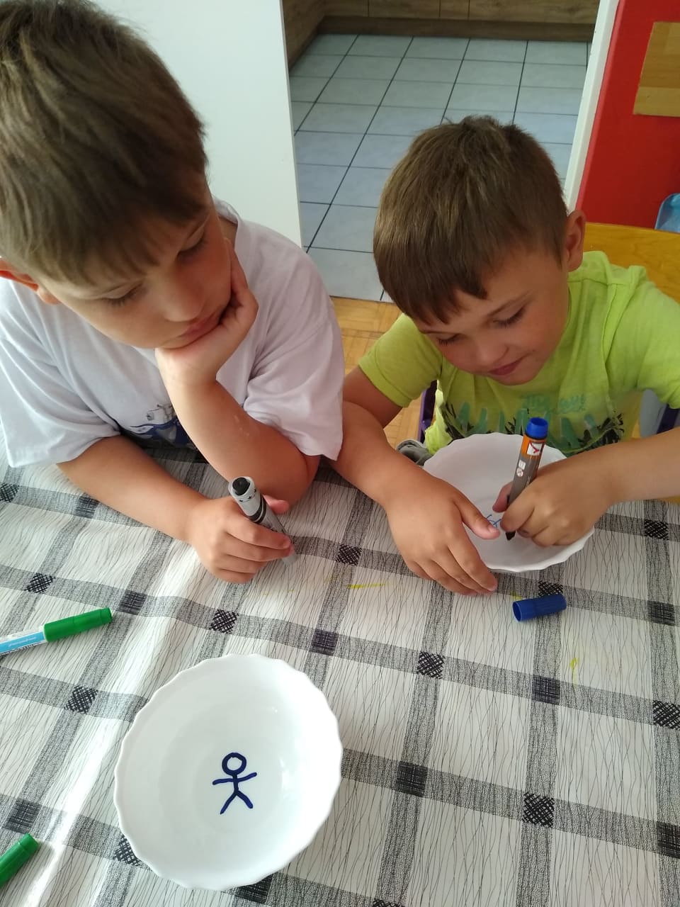 chłopcy malują markerami na talerzach