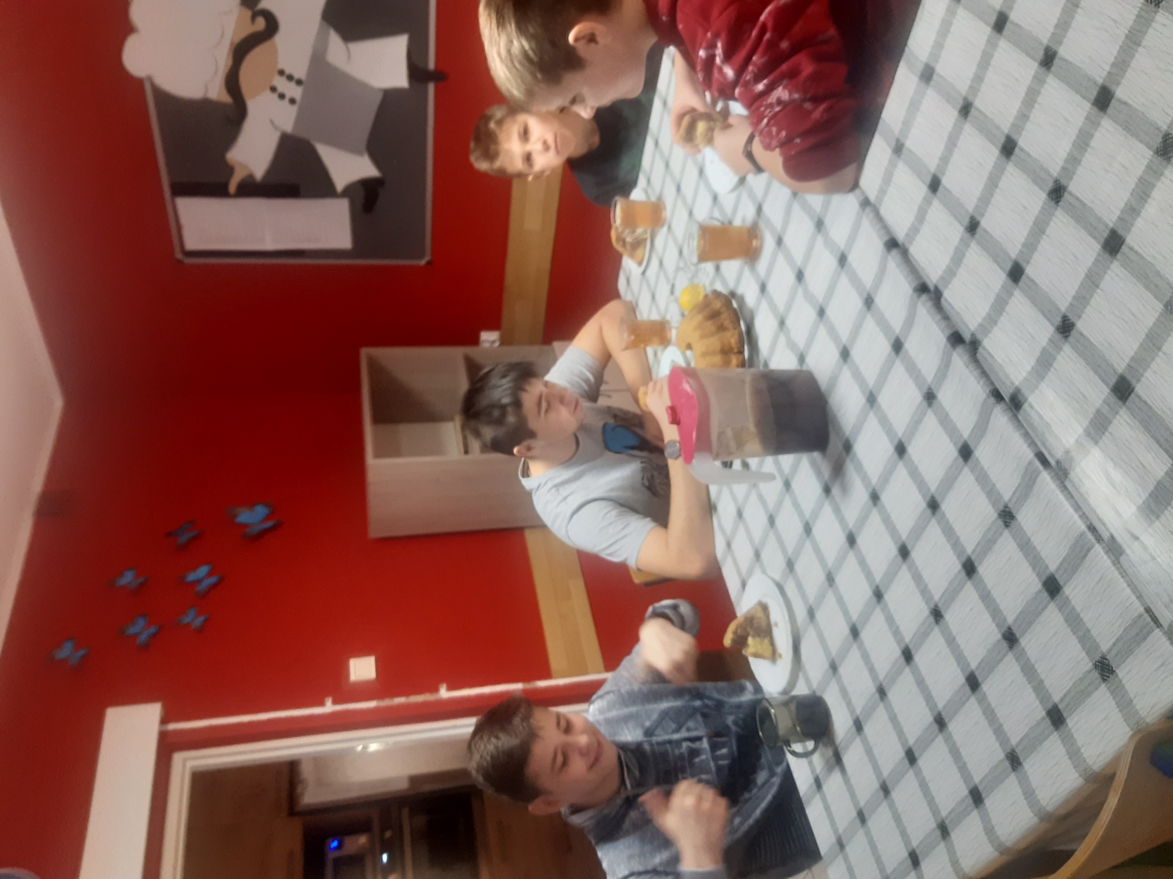 czterej wychowankowie siedzą przy stole i jedzą babkę