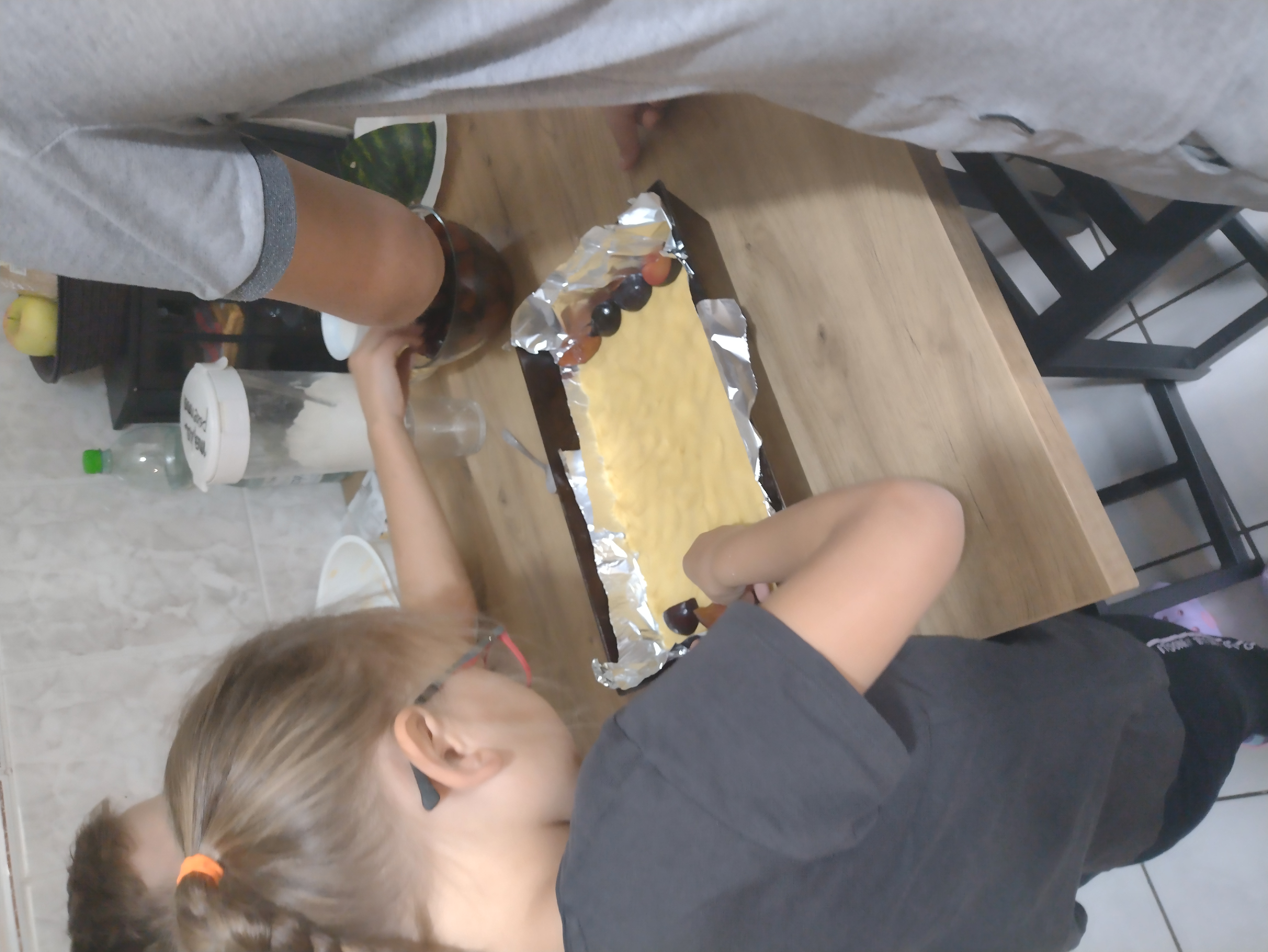 dzieci układają owoce na blaszce ciasta