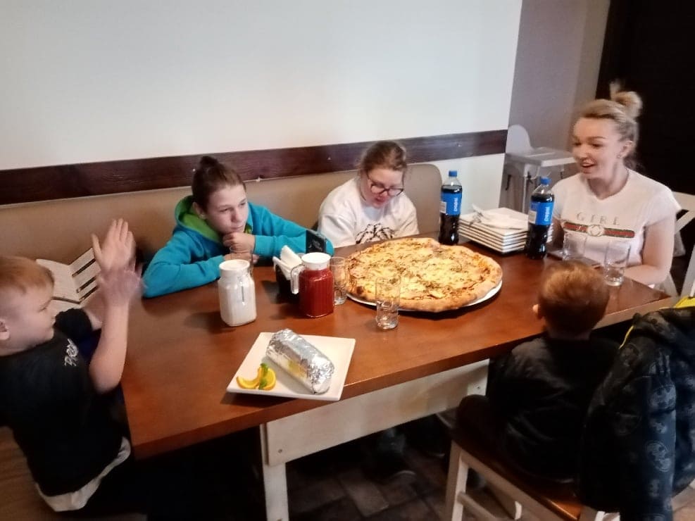 dzieci z wychowawcą przy stole w pizzerii