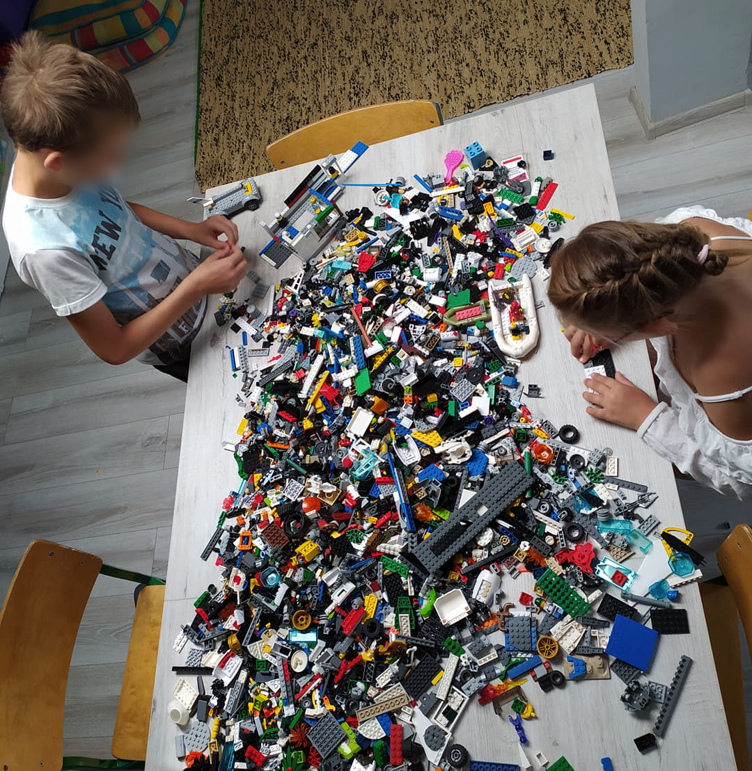 dzieci przy stole pełnym klocków LEGO