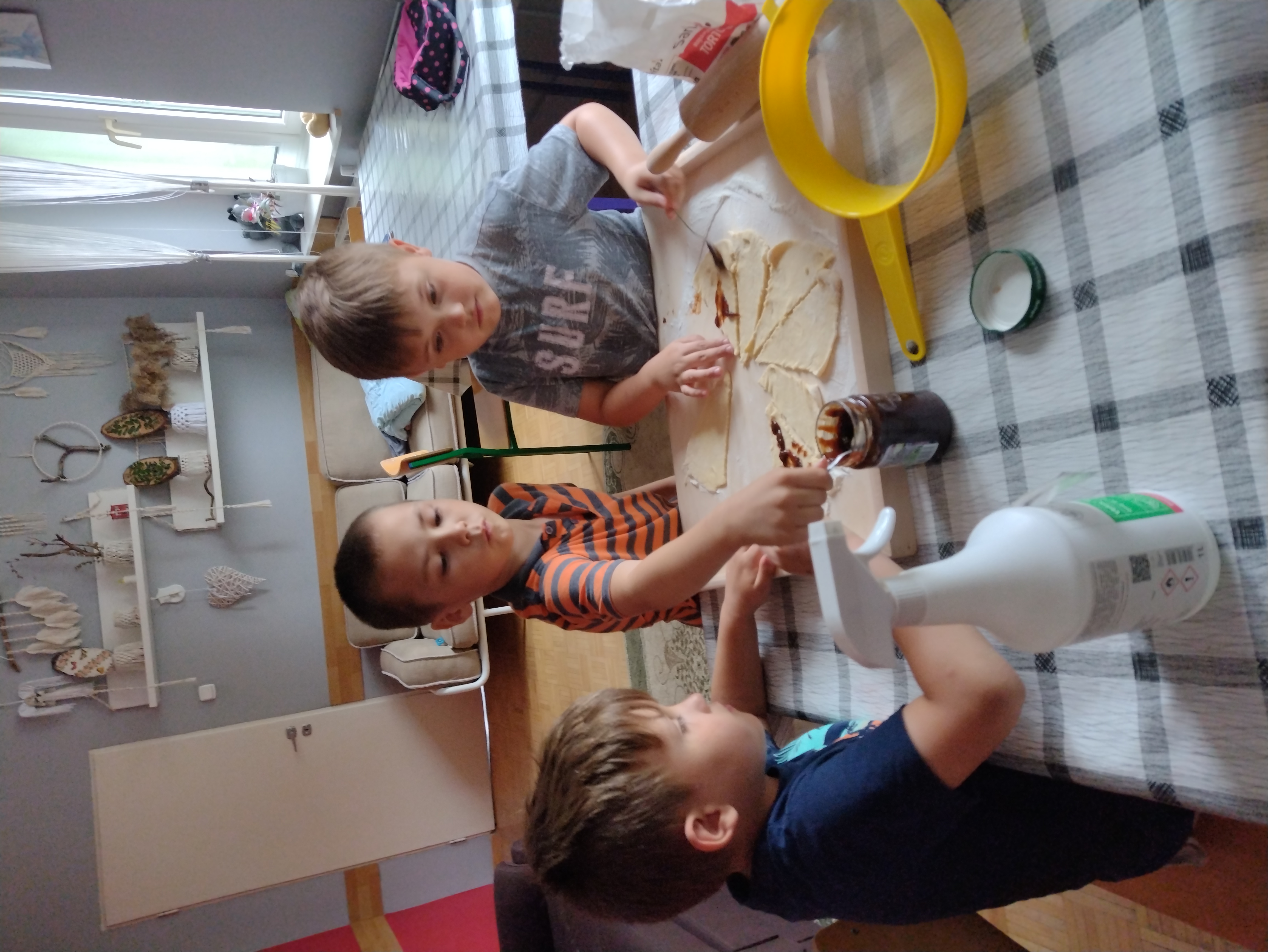 trzej chłopcy smarują powidłami ciasto na rogaliki