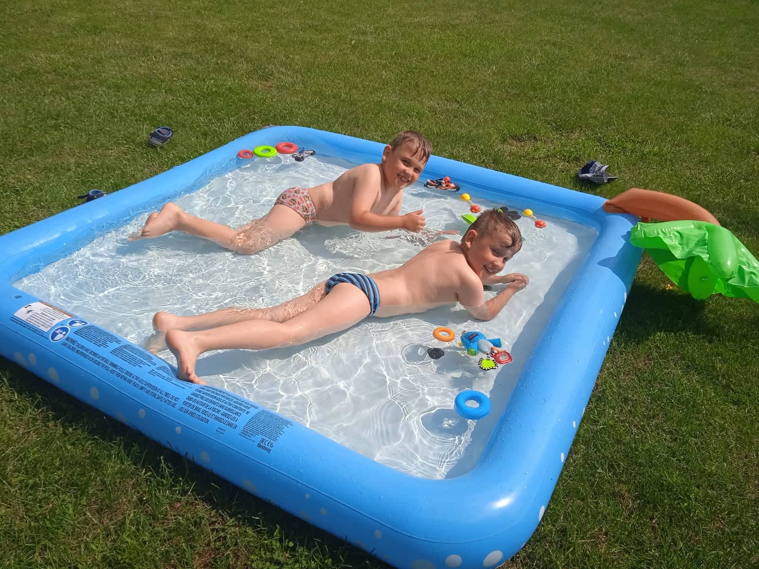 chłopcy leżą we wodzie w mini basenie