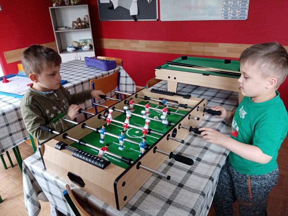 dwaj chłopcy grają w piłkarzyki stołowe